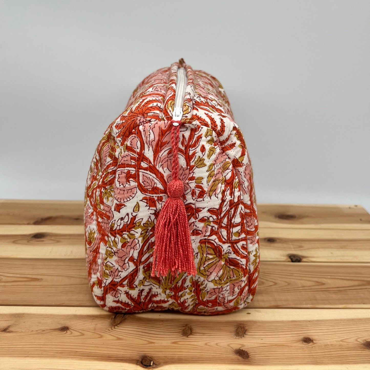 Decorative woven basket with a red tassel on a wooden surface
